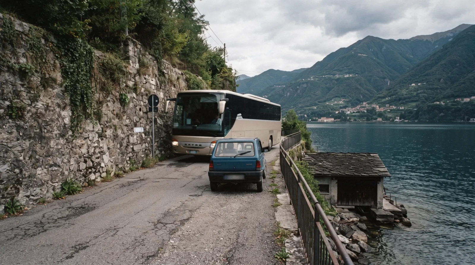 A narrow lakeside road squeezed between old houses and the water with a car edging through, driving in Lake Como