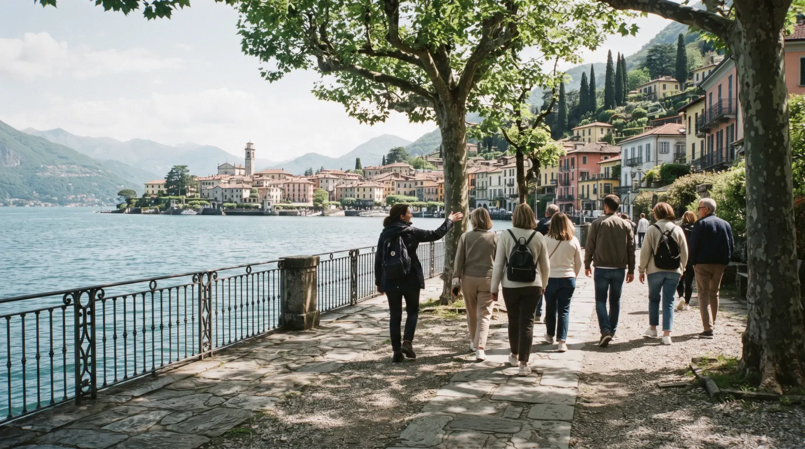 A small group walking a shaded lakeside path below terraced gardens on a Lake Como tour