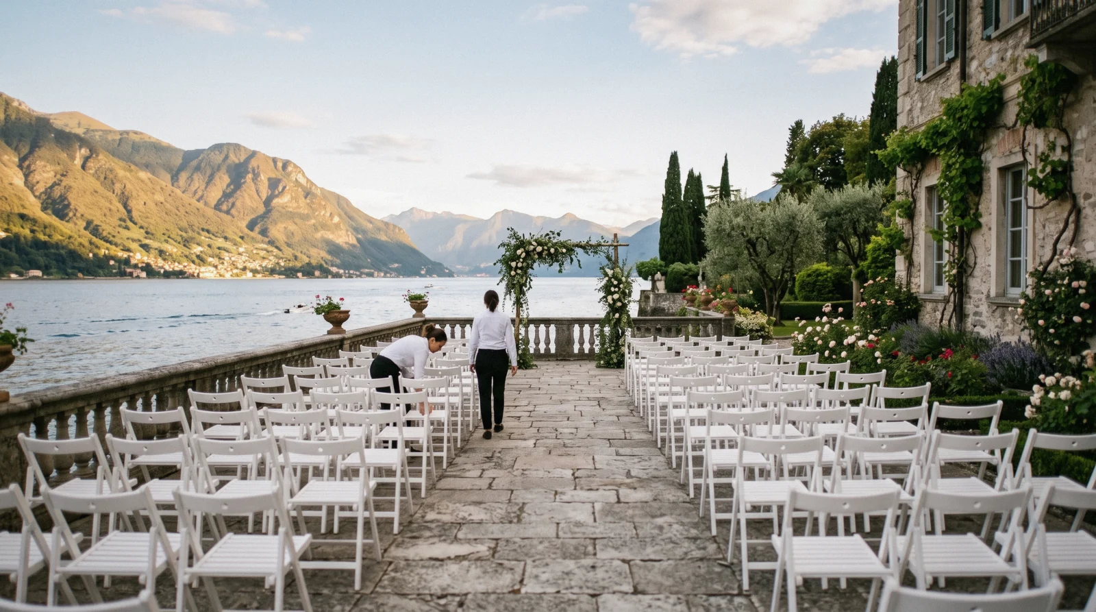 A wedding party on a stone terrace above the water with boats below, a classic Lake Como wedding setting