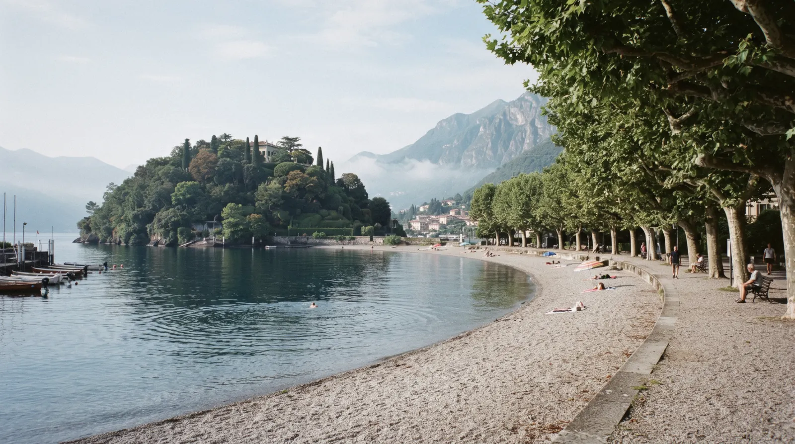 The crescent bay and lakefront promenade at Lenno on Lake Como, with the wooded Dosso di Lavedo peninsula closing the far side of the water