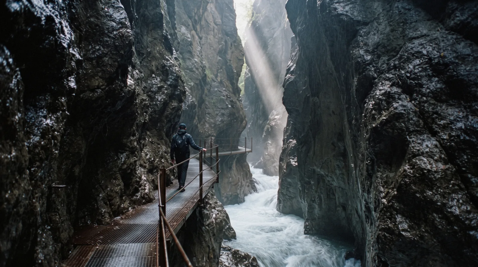 A steel walkway bolted to the wet rock wall of a narrow gorge above a green torrent, the Orrido di Bellano on Lake Como