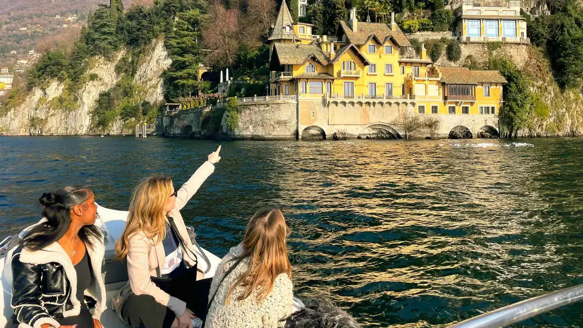 Small tour boat passing lakeside villas in the first basin of Lake Como